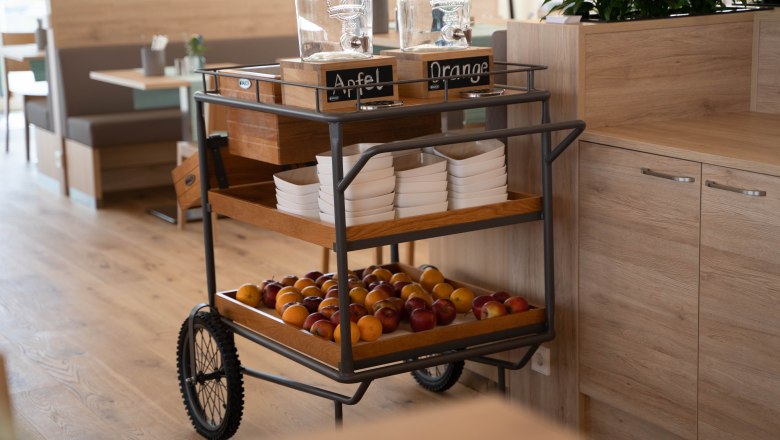 Breakfast area with a trolley full of fruit and drinks dispensers.