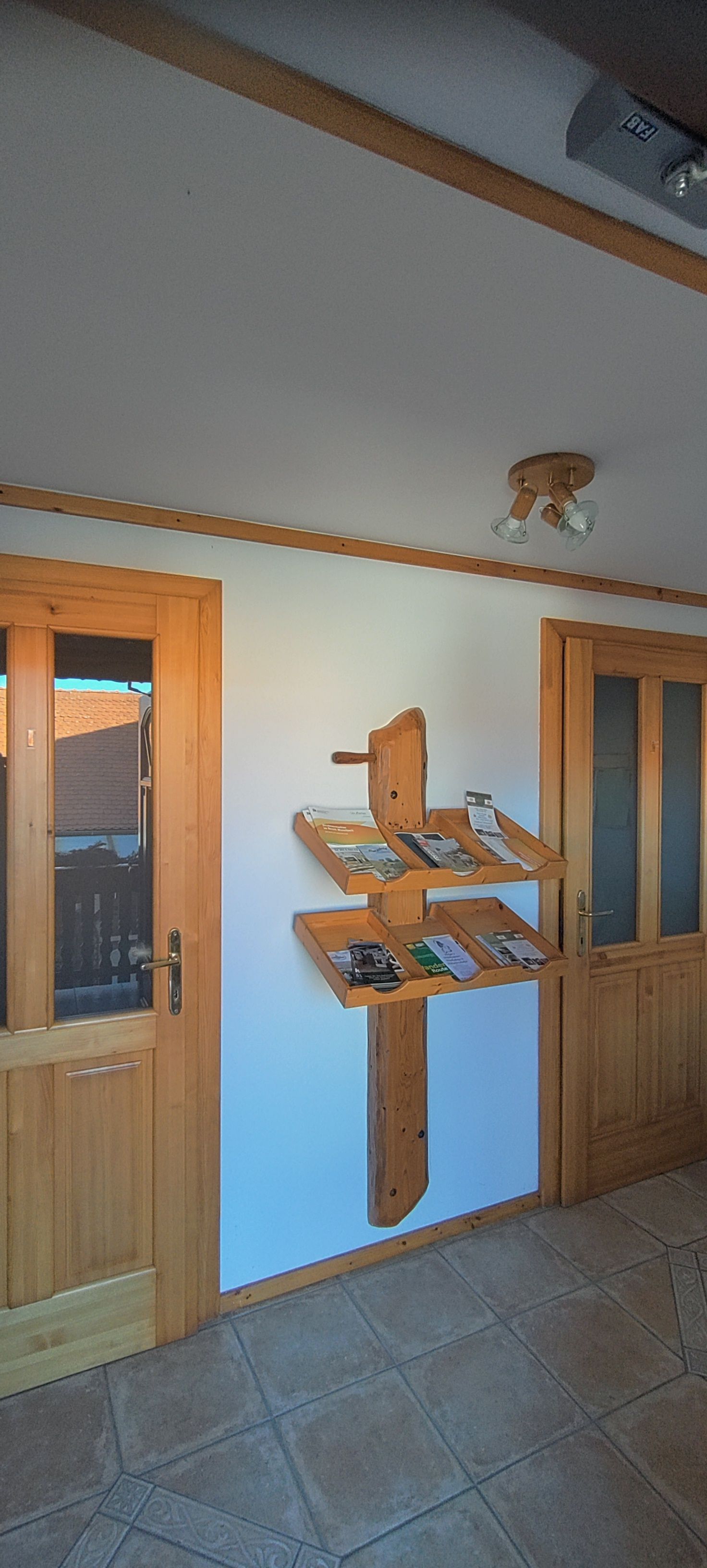 A wooden shelf with brochures on a white wall between two wooden doors.