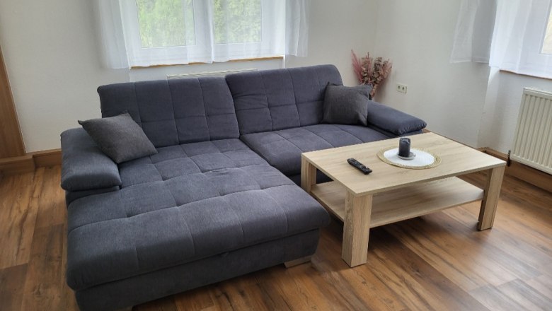 Living room with gray corner sofa and wooden table in front of a window.