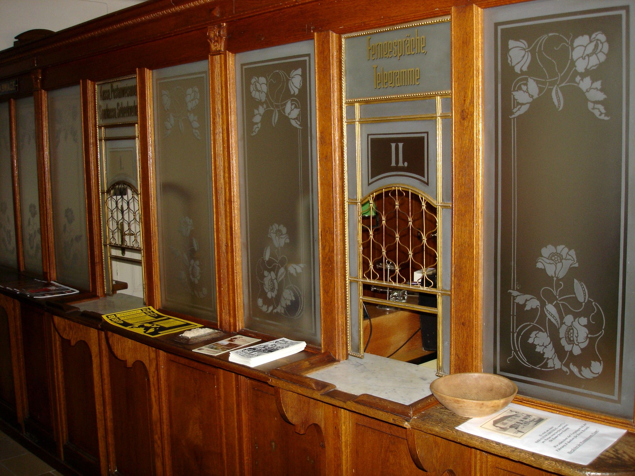 Historic post office counter with wooden paneling and glass windows.