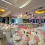 Large banqueting hall with many tables and a laid table.