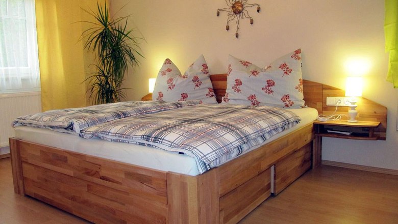 Cozy bedroom with double bed, plants and wall decoration.