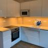 Modern kitchen with white cupboards, wooden worktop, built-in oven and sink.
