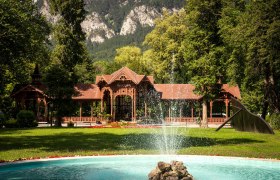 Surrounded by majestic mountains and lush greenery, the historic pavilion exudes an inviting atmosphere. The gentle sounds of water gushing from the fountain harmonize perfectly with the picturesque backdrop and invite you to enjoy the beauty of nature.