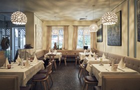 Elegant restaurant with laid tables, modern lamps and art on the walls.