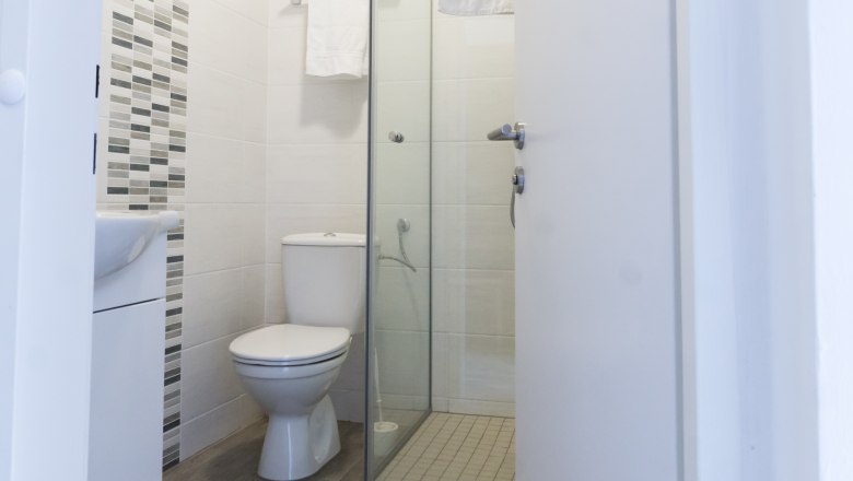 Modern bathroom with toilet, shower and towel rail.