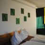 A room with two beds, green pictures of keys on the wall and a yellow painting.