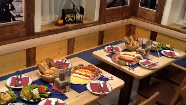 A table set in a rustic restaurant with bread, cold cuts and salads.
