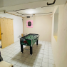 A games room with a table football table and a dartboard on the wall.