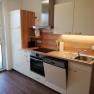 Modern kitchen unit with wooden worktop, sink, stove and dishwasher.