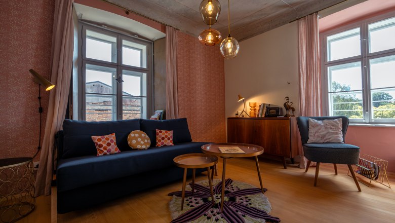 Cozy living room with sofa, armchairs, carpet and hanging lamps.