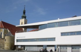 Modern building with church tower in the background in W&ouml;lbling.
