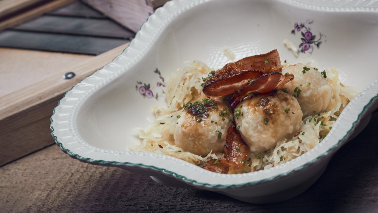 Traditional dish with dumplings, bacon and sauerkraut in a decorative bowl.