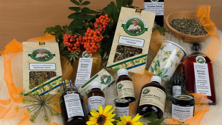 Various herbal products from herbalist Weidinger, surrounded by flowers and berries.