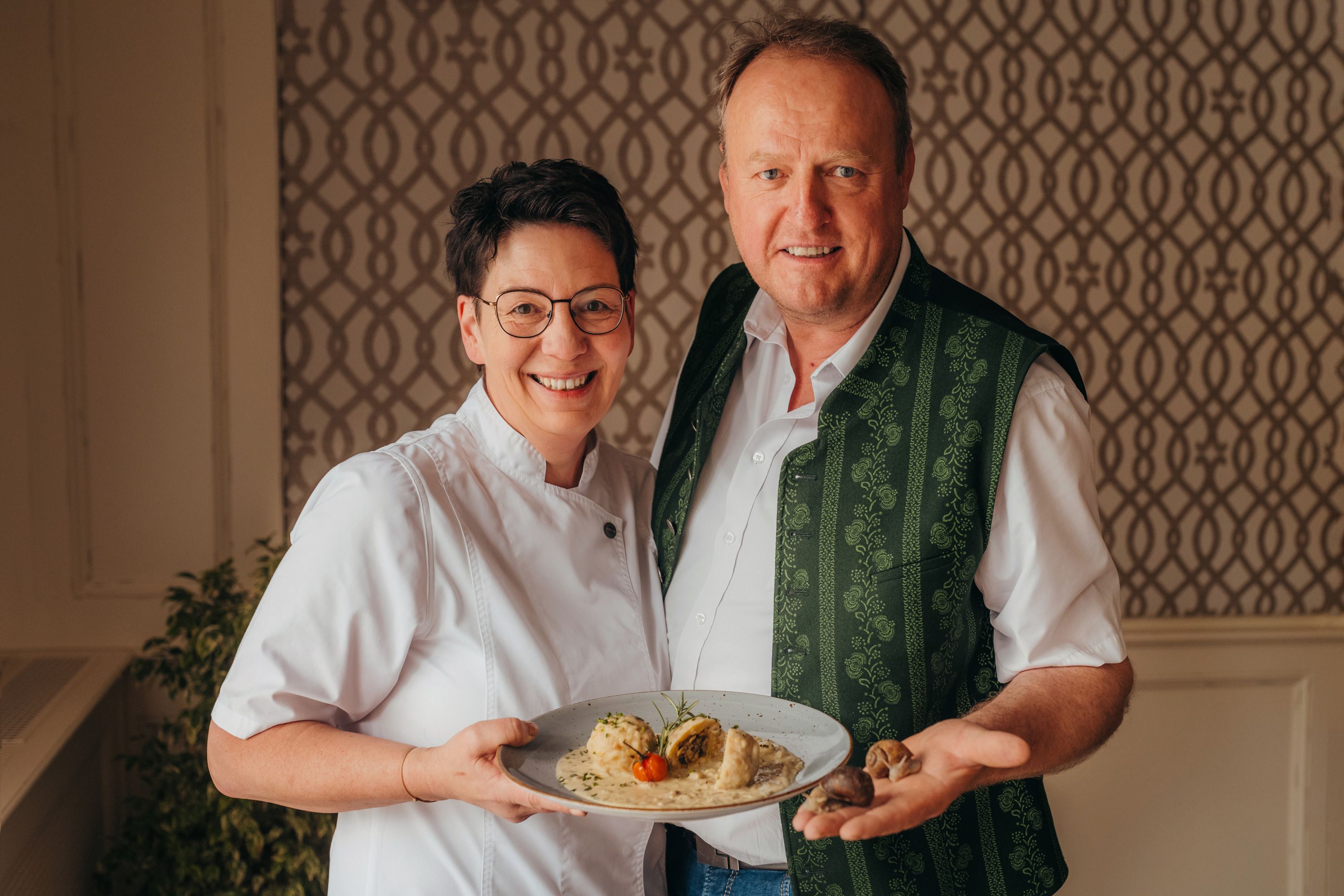 A man and a woman are smiling and holding a plate of food.