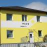 Yellow house with the inscription 'Haus' and a sun on the façade.