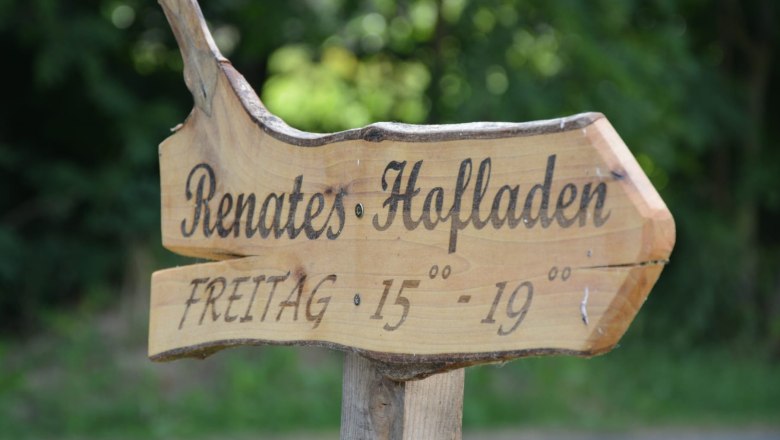 Wooden sign with the inscription 'Renates Hofladen' and opening hours 'Freitag 15-19 Uhr'.