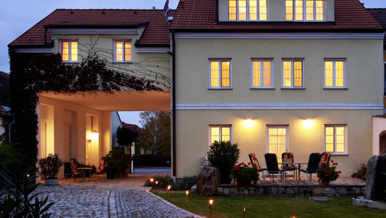 Illuminated building with paved path and garden furniture in the foreground.