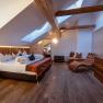 Cozy hotel room with wooden beams, skylights, large bed and leather armchair.