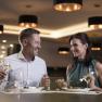 A couple is sitting in an elegant restaurant enjoying a dinner with wine.