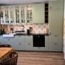 Kitchen with white cupboards, wooden worktop and tiled splashback.