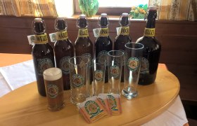 Various Fiaker Bräu beer bottles and glasses on a table.