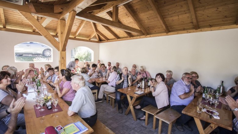 People sitting at wooden tables in a wine tavern and gossiping.
