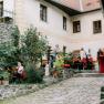 An inner courtyard with people sitting and standing at tables, surrounded by plants and a stone building.