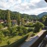 View from a balcony of a green landscape with houses and hills in the background.