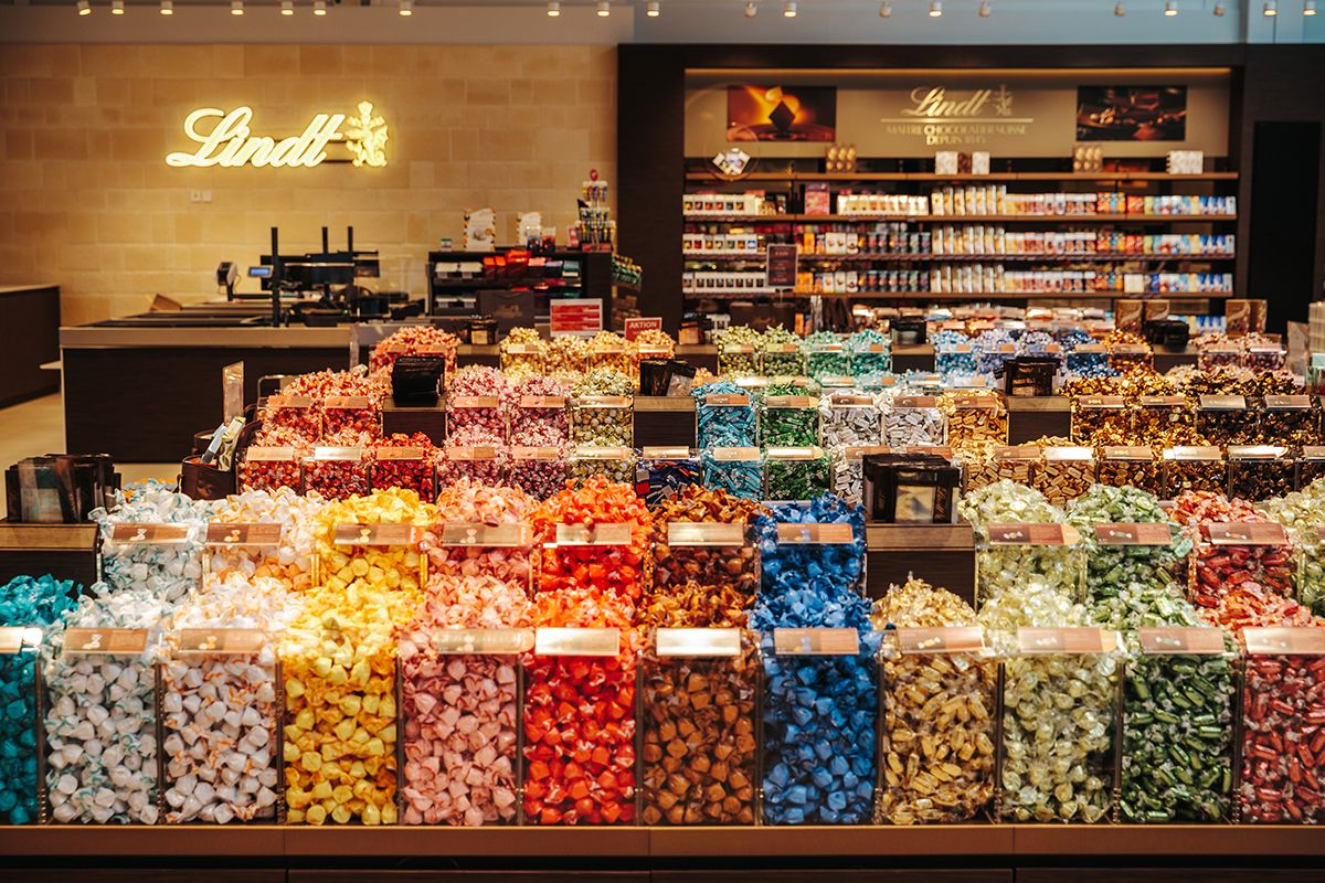 A store with a large selection of colorful Lindt chocolates in transparent containers.