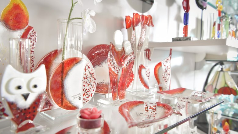 Glass decorations in red and white on a shelf.