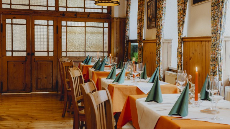 A chef in a black uniform cooks in a professional kitchen with several pots and ladles on the wall.