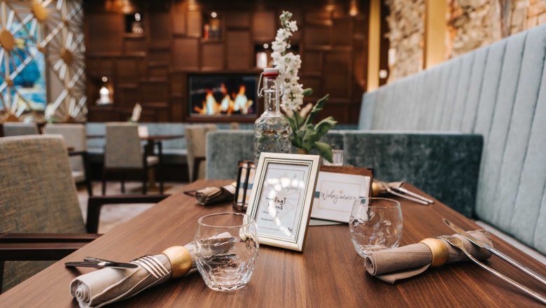 A stylishly laid table in a caf&eacute; with wooden decor and a fireplace in the background.