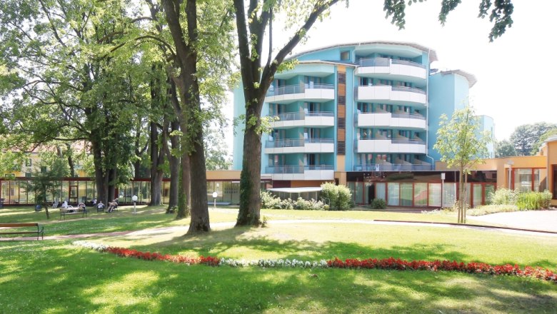 Modern building with balconies and garden in the foreground.