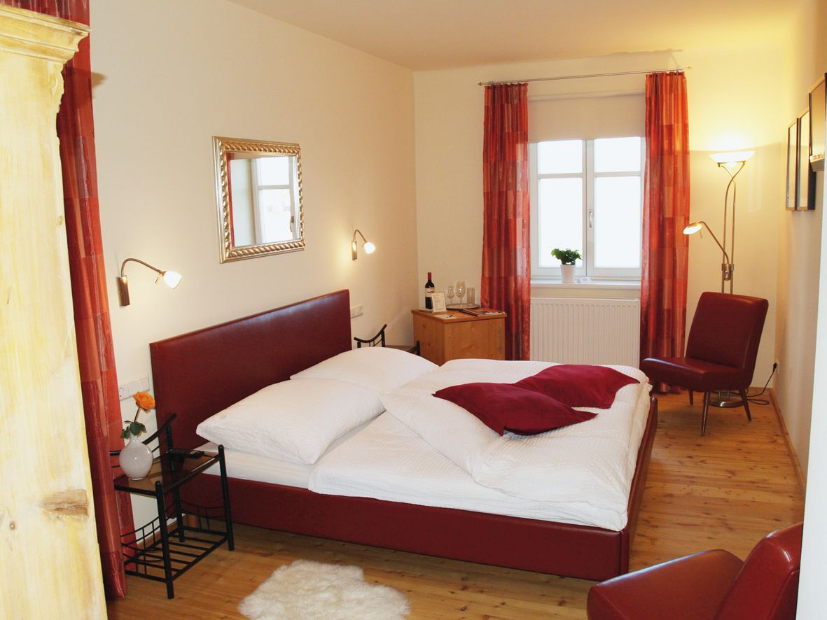 Cozy bedroom with red bed and decor.