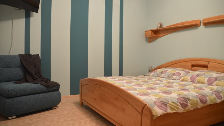 Bedroom, © Eva Stuhr Bedroom with striped wall, wooden bed and sofa.