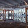 Interior view of a hotel pool with sun loungers and glass front.