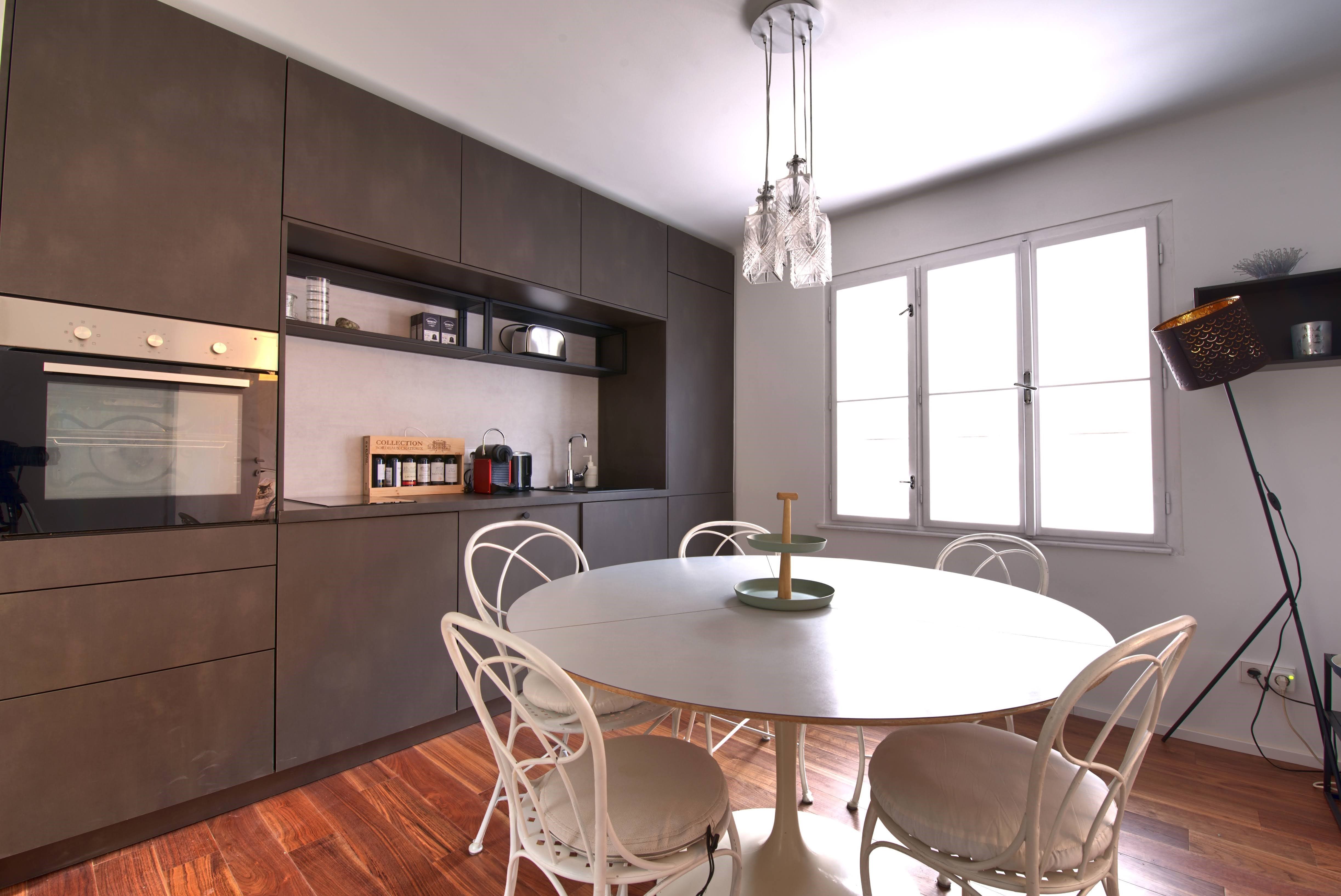 Modern kitchen with dining table, chairs and hanging lamp.