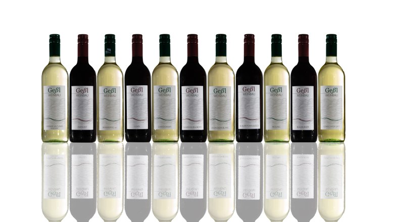 A series of wine bottles with different varieties and labels that are reflected on a reflective surface.