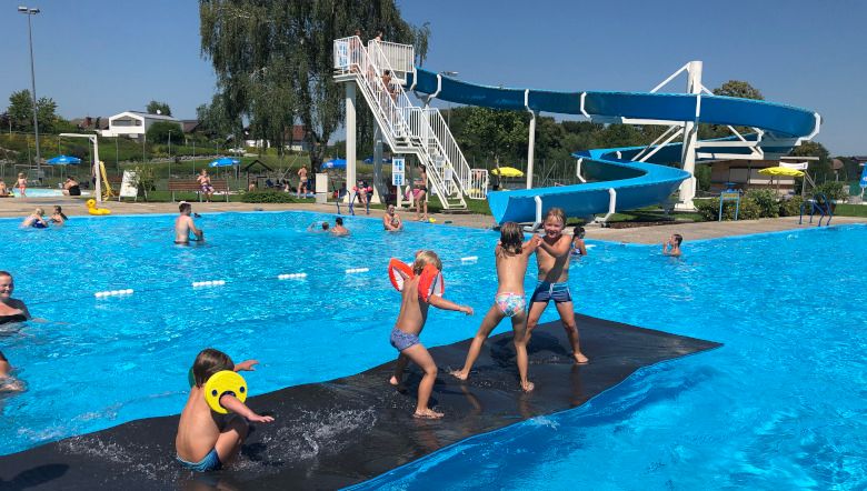 Children play on a floating mat in front of a water slide at the Neuhofen an der Ybbs outdoor pool.
