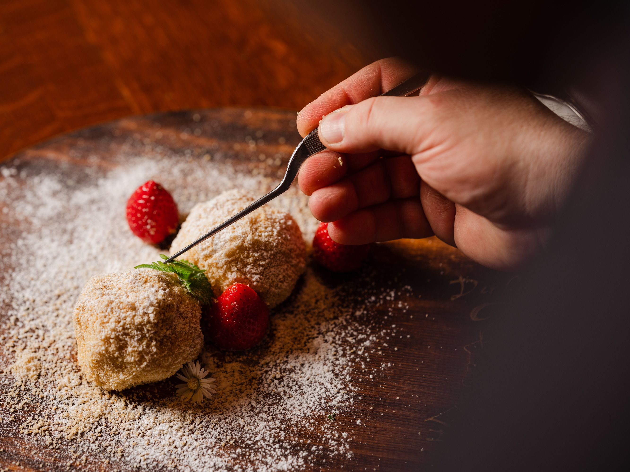 Hand-decorated dessert with strawberries and mint on a wooden platter.