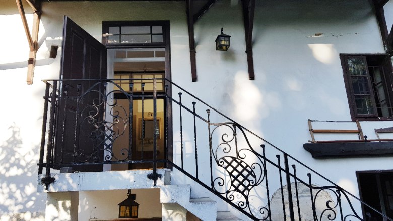 Entrance area of a house with staircase and wrought-iron railing.