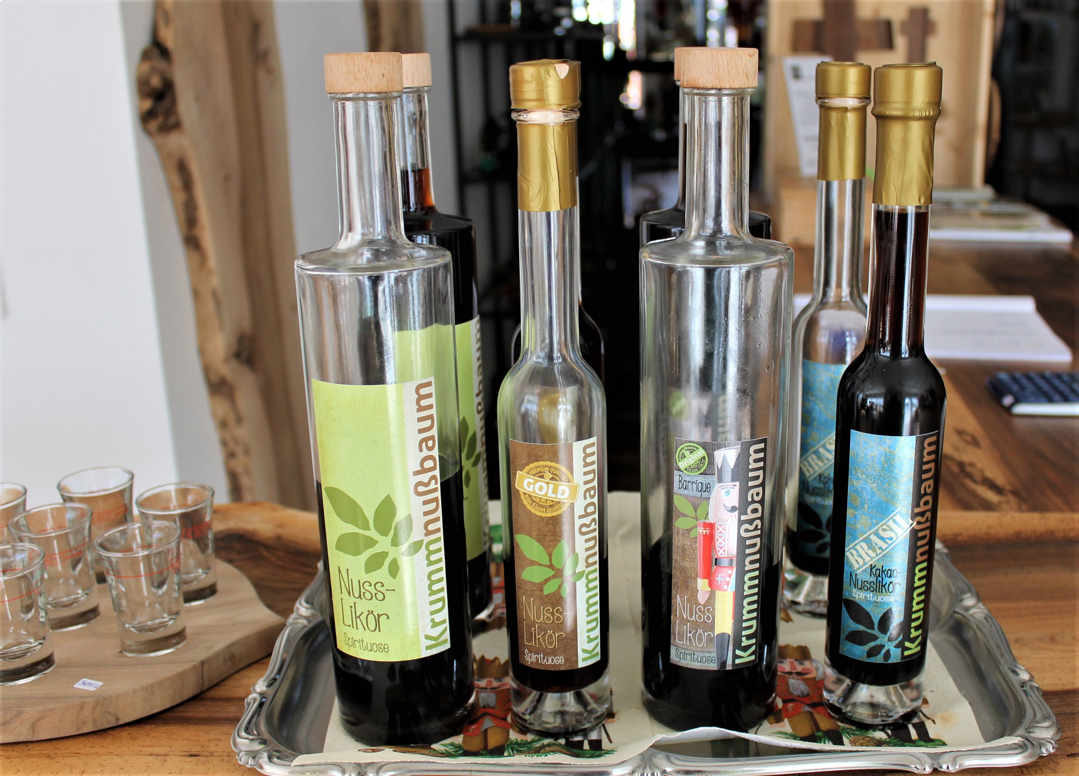 Several bottles of nut liqueur on a tray with glasses next to them.