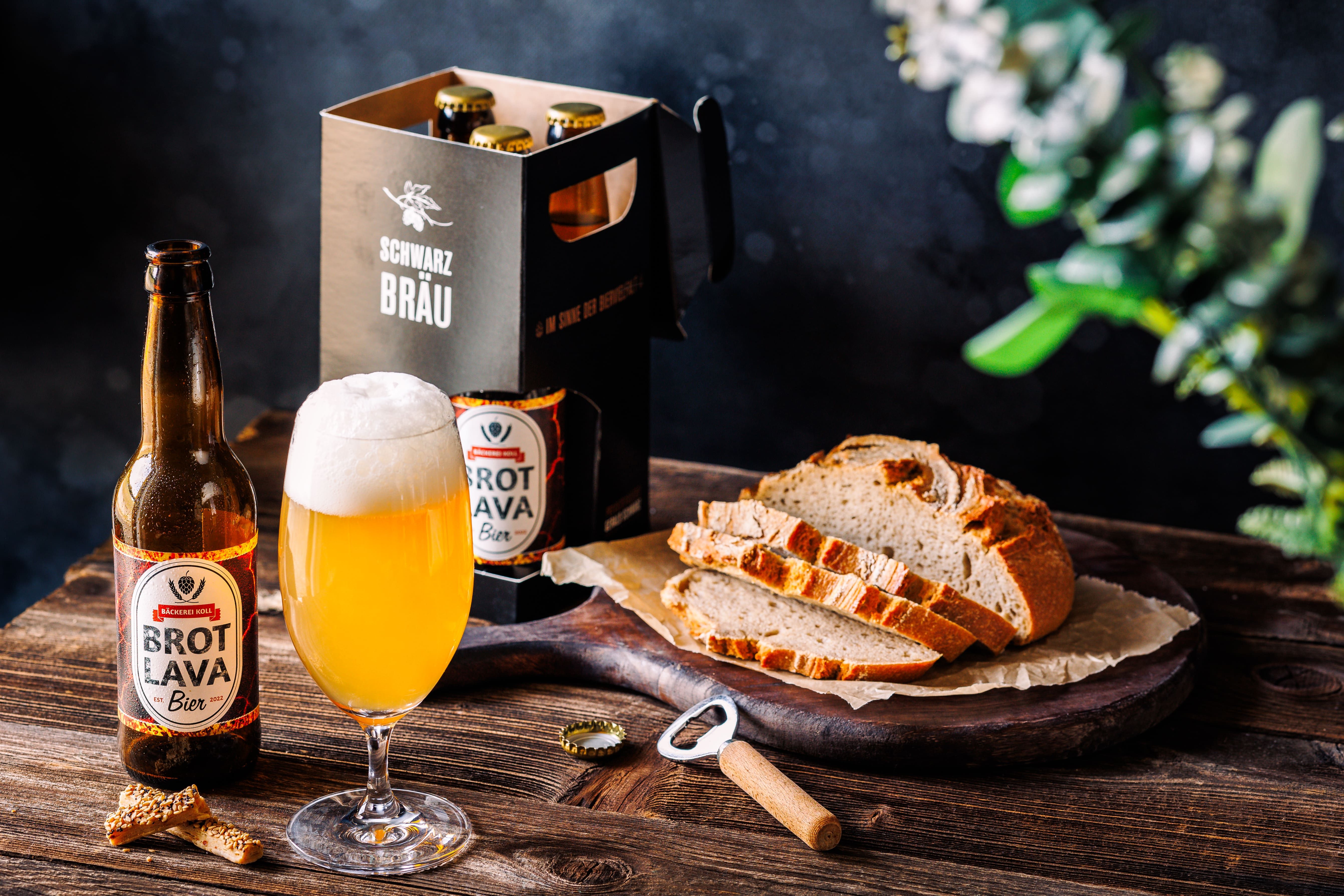 A bottle of lava beer next to a filled glass and sliced lava bread on a wooden table.