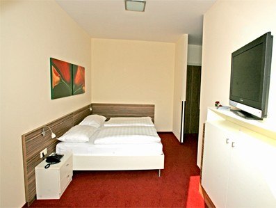 Hotel room with double bed, red carpet and mural.
