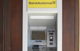 An ATM with a yellow sign and Raiffeisen logo.