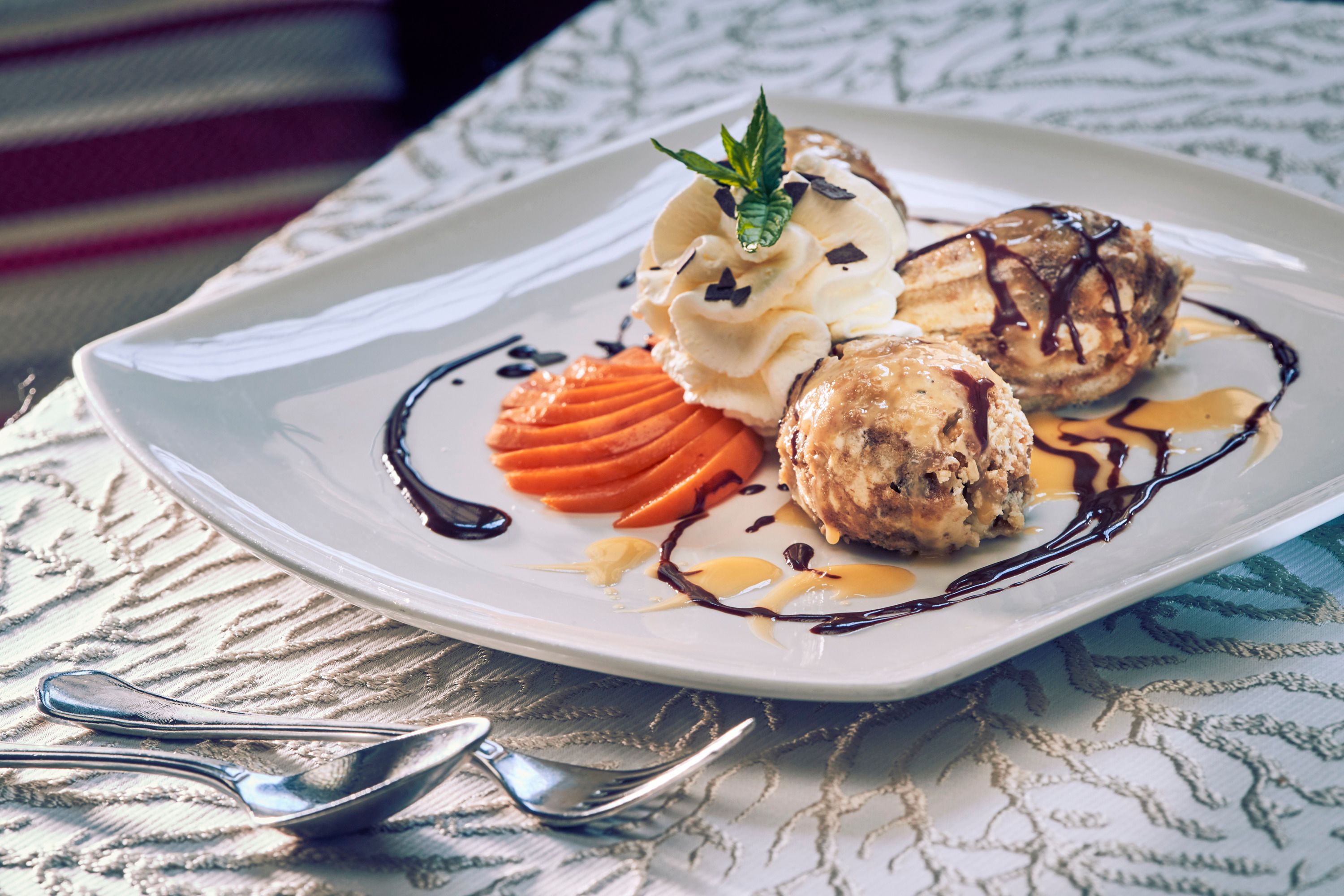 A dessert plate with Malakoffnockerl, cream, chocolate sauce and decorative fruit.