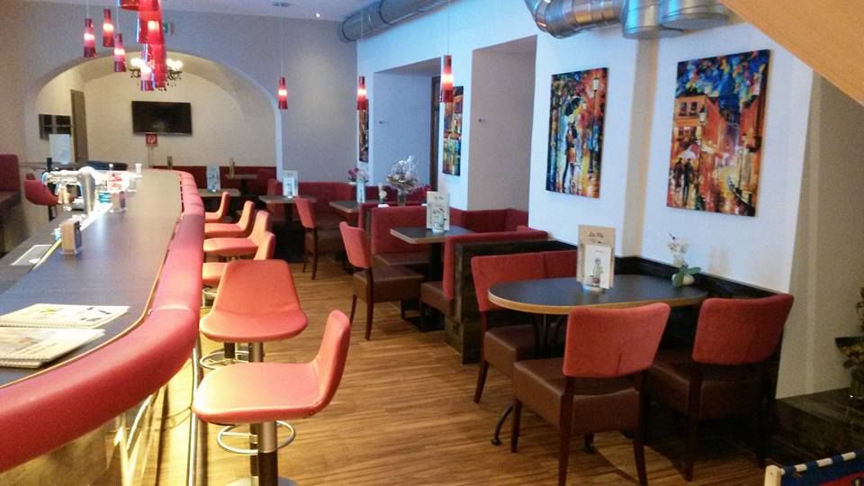 Interior view of a modern café with red chairs and bar stools.
