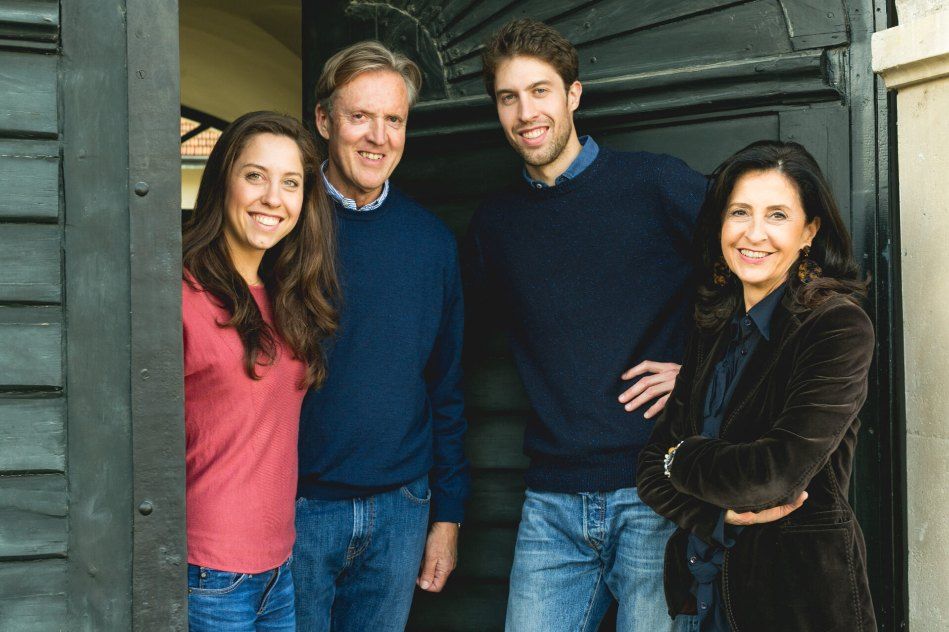 Four people stand smiling in a doorway, two men and two women, all in casual clothes.