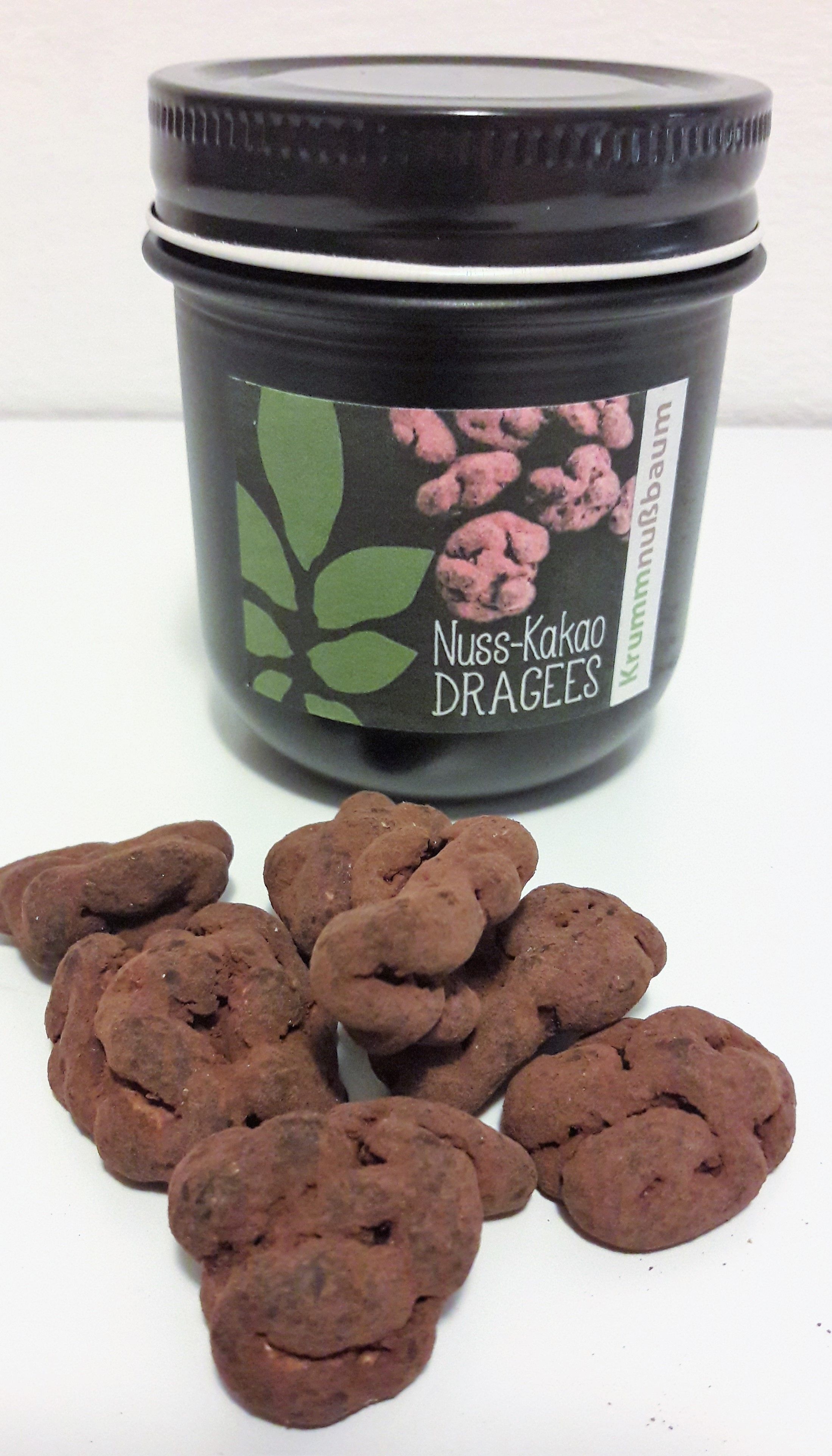 A jar labeled 'Nuss-Kakao Dragees' and a few dragees in front of it.